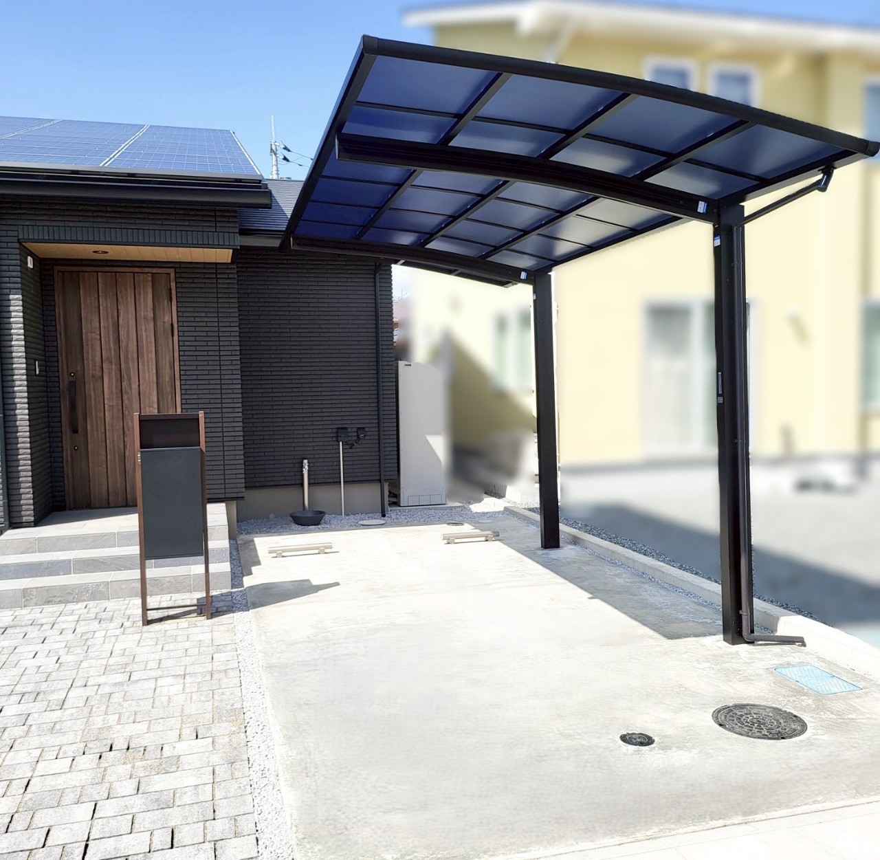施工後　カーポート　YKK　アリュース 600タイプ 1台用　色：カームブラック　屋根材：熱線遮断ポリカーボネート　色：アースブルー（マット調）<br />
